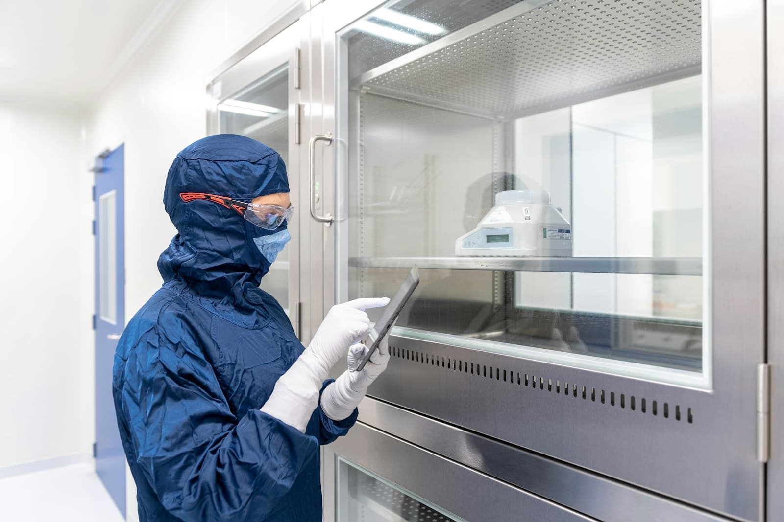 Quality professional in protective clothing reviewing records on a tablet