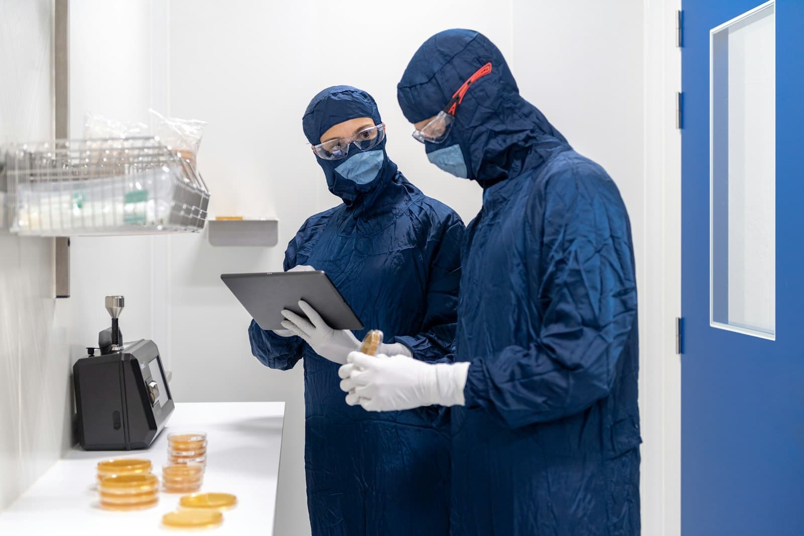 Two professionals in cleanroom suits reviewing data